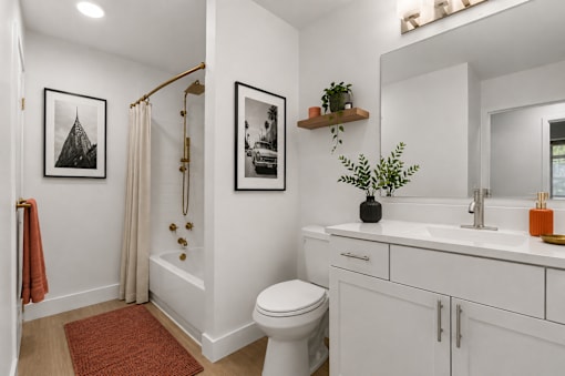 A white bathroom with a toilet, sink, and pictures on the wall.