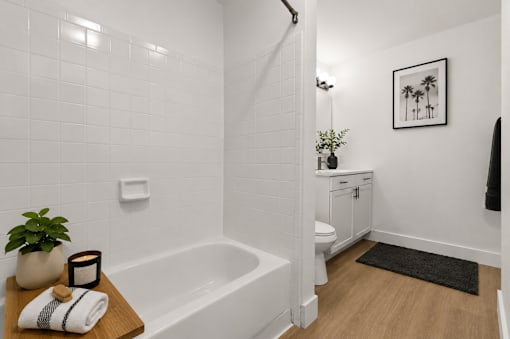 A white bathroom with a black towel hanging on the door.