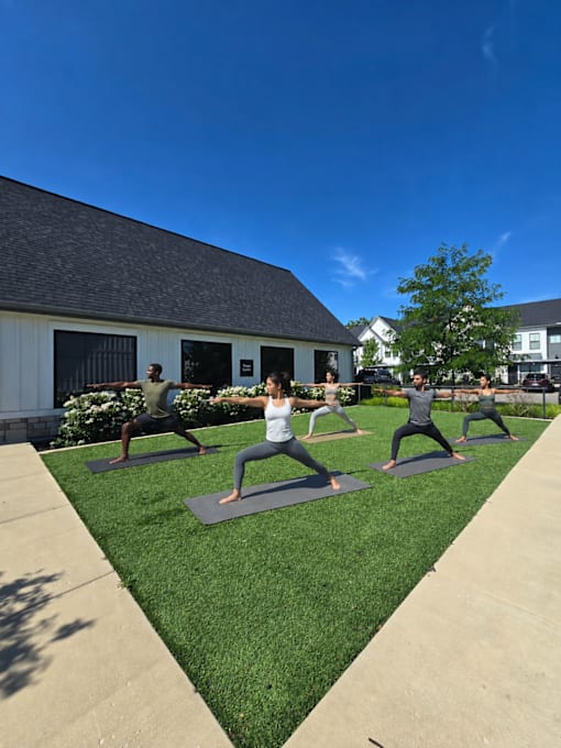 A group of people practicing yoga on mats outside a building.