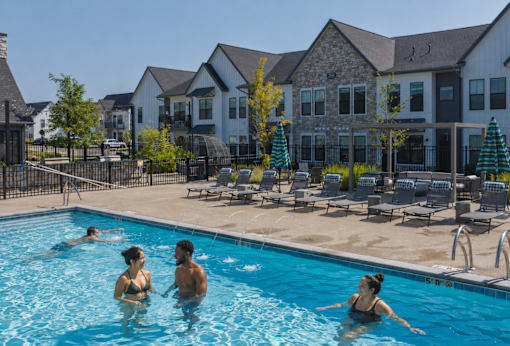 People are swimming in a pool with a resort in the background.