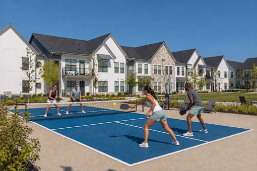 Four people playing tennis on a tennis court.