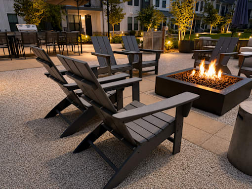 A fire pit is surrounded by chairs on a patio.