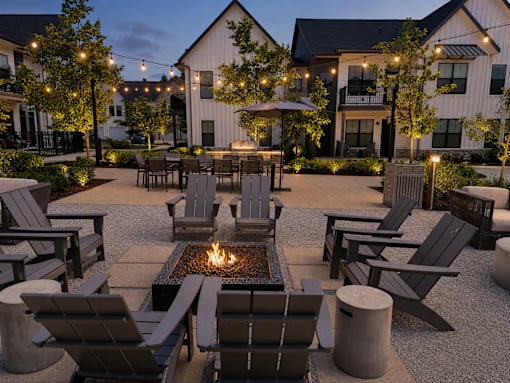 A fire pit is surrounded by chairs in a courtyard.