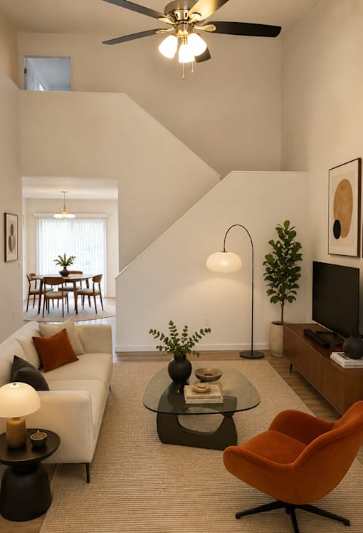 A living room with a white couch, a black coffee table, and a television.