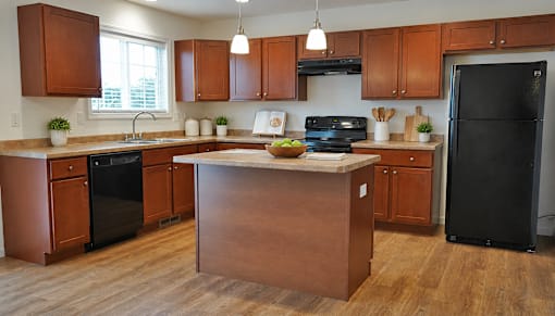 A kitchen with wooden cabinets and a black refrigerator.
