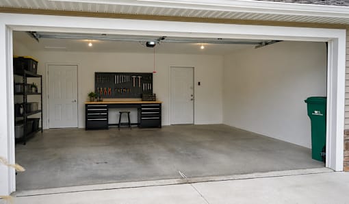 A garage with a workbench and storage drawers.