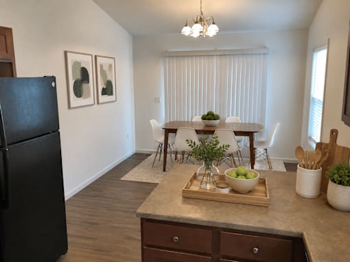 A kitchen with a black refrigerator and a dining table with chairs.