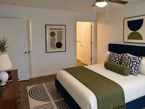 A bedroom with a bed, a lamp, and a framed picture on the wall.