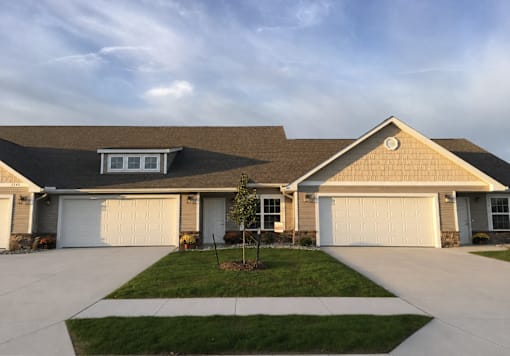 A house with a brown roof and two white garage doors.