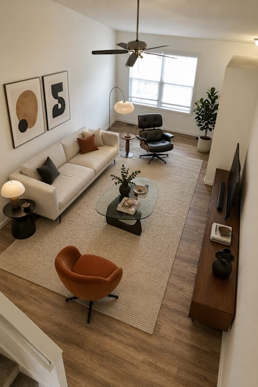 A living room with a white couch, a brown chair, and a ceiling fan.