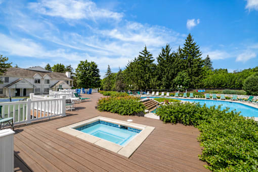 Outdoor pool deck with hot tub and seating at Village Club of Farmington Hills Apartments, Farmington Hills, 48331