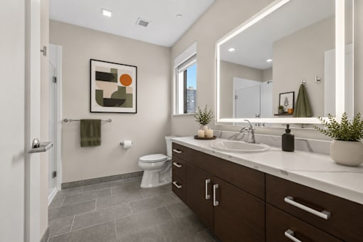 A bathroom with a toilet, sink, and mirror.
