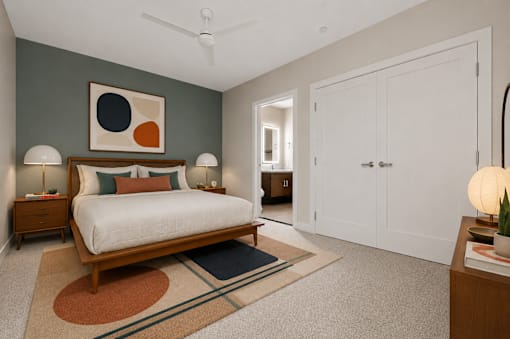 A bedroom with a bed, two lamps, and a painting on the wall.