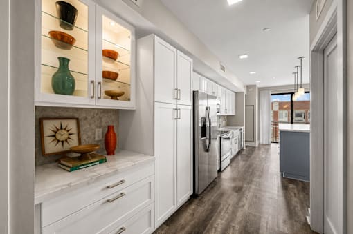 A kitchen with white cabinets and a wooden floor.