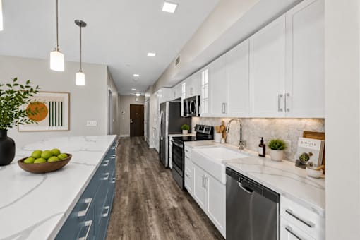 A modern kitchen with white cabinets and a wooden floor.