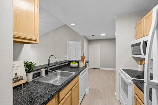 Modern kitchen with dark countertops and oak cabinets at Village Club of Farmington Hills Apartments, Farmington Hills, Michigan