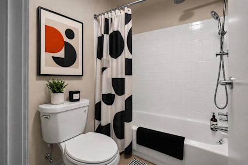 Contemporary bathroom with geometric shower curtain and white tile at Village Club of Farmington Hills Apartments, Michigan