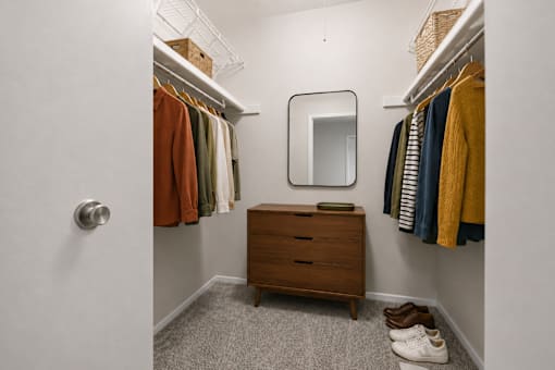 Walk-in closet with hanging rods and dresser at Village Club of Farmington Hills Apartments, Farmington Hills, MI 48331