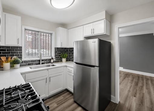 A modern kitchen with a stainless steel refrigerator and a black and white tiled backsplash.