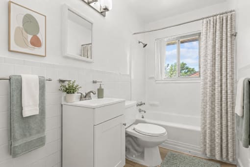 A white bathroom with a towel hanging on the wall.