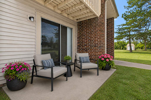 A patio with a chair and a table with a potted plant on it.