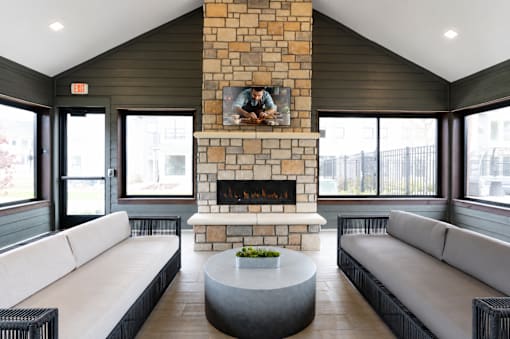A modern living room with a stone fireplace and a painting above it.