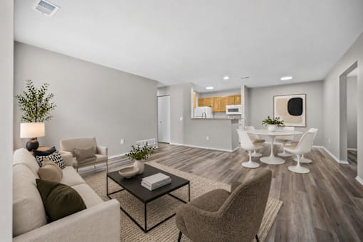 A modern living room with a grey sofa, a coffee table, and a dining table set up.