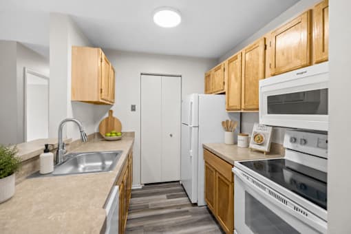 A kitchen with white appliances and wooden cabinets.