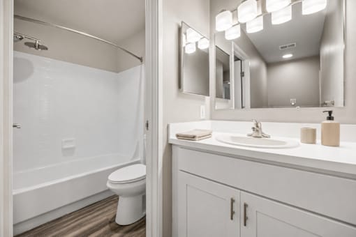 A white bathroom with a toilet, sink, and mirror.