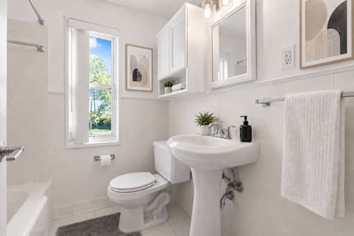 A white bathroom with a toilet, sink, and mirror.