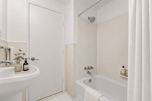 A white bathroom with a tub, sink, and shower.