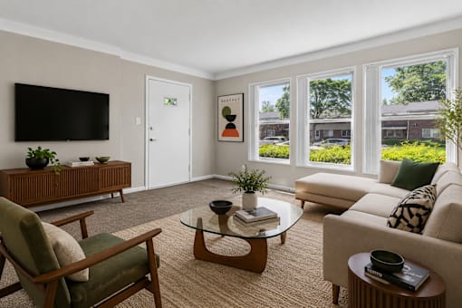 A living room with a green chair, a white sofa, and a glass coffee table.