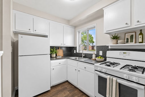 A white kitchen with a stove and a refrigerator.