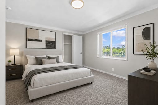 A bedroom with a large bed and a window overlooking a green landscape.