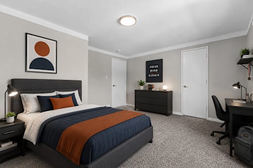A bedroom with a bed, desk, and chair.