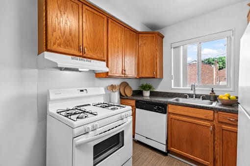 A kitchen with a white gas stove and wooden cabinets.