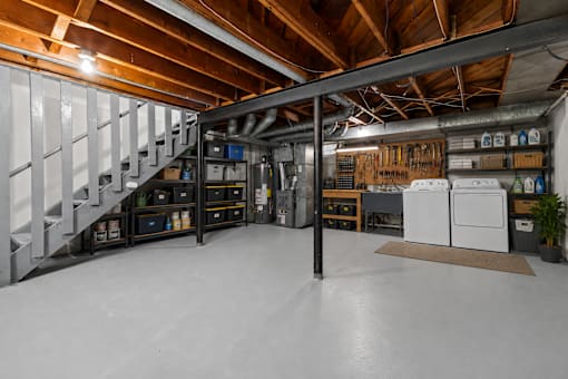 A large, empty room with a staircase and a workbench.