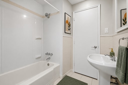A white bathroom with a tub, sink, and mirror.