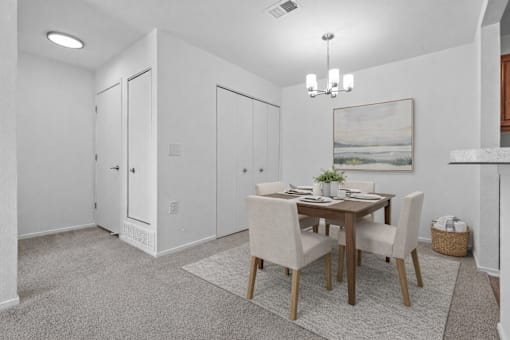 A dining room with a table set for two and a painting on the wall.