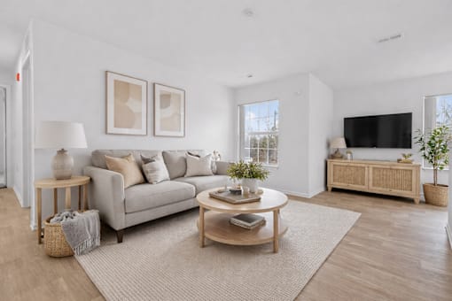 A living room with a grey couch, a wooden coffee table, and a flat screen TV.