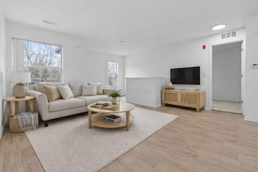 A living room with a white couch, a wooden coffee table, and a flat-screen TV.
