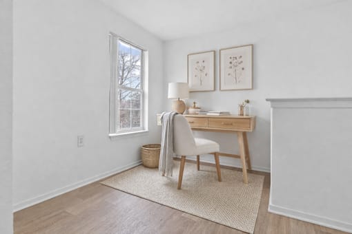 A room with a desk, chair, and pictures on the wall.