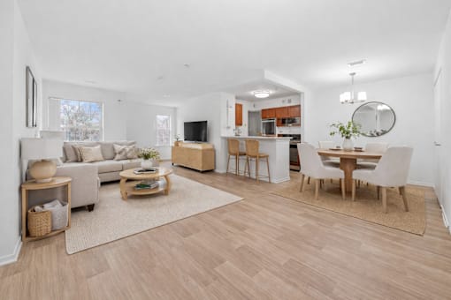 A living room with a grey couch, a wooden coffee table, and a dining table with chairs.