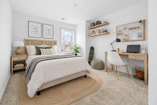 A bedroom with a bed, desk, chair, and shelves.