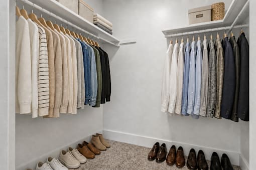 A white closet with clothes and shoes.