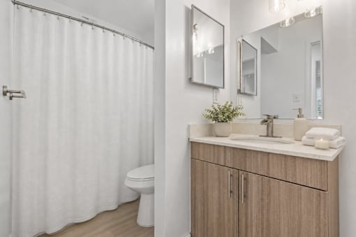 A white bathroom with a toilet, sink, and shower curtain.