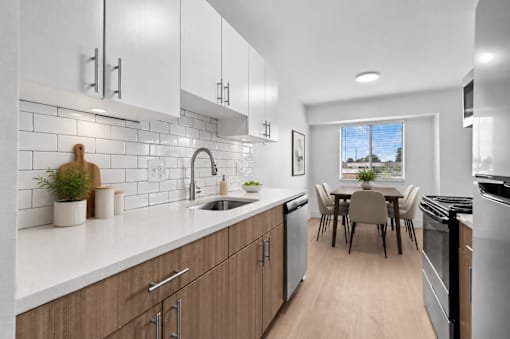 A modern kitchen with wooden cabinets and a dining table.