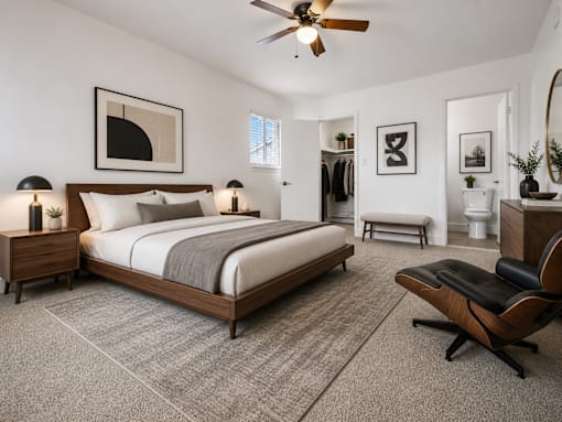 A bedroom with a large bed, a chair, and a ceiling fan.