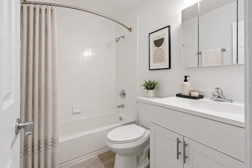 A white bathroom with a toilet, sink, and shower.