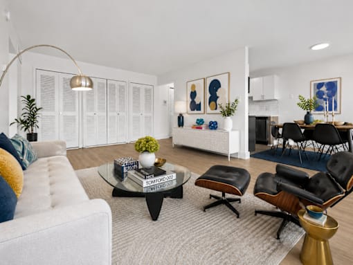 A living room with a white couch, a coffee table, and a dining table with chairs.